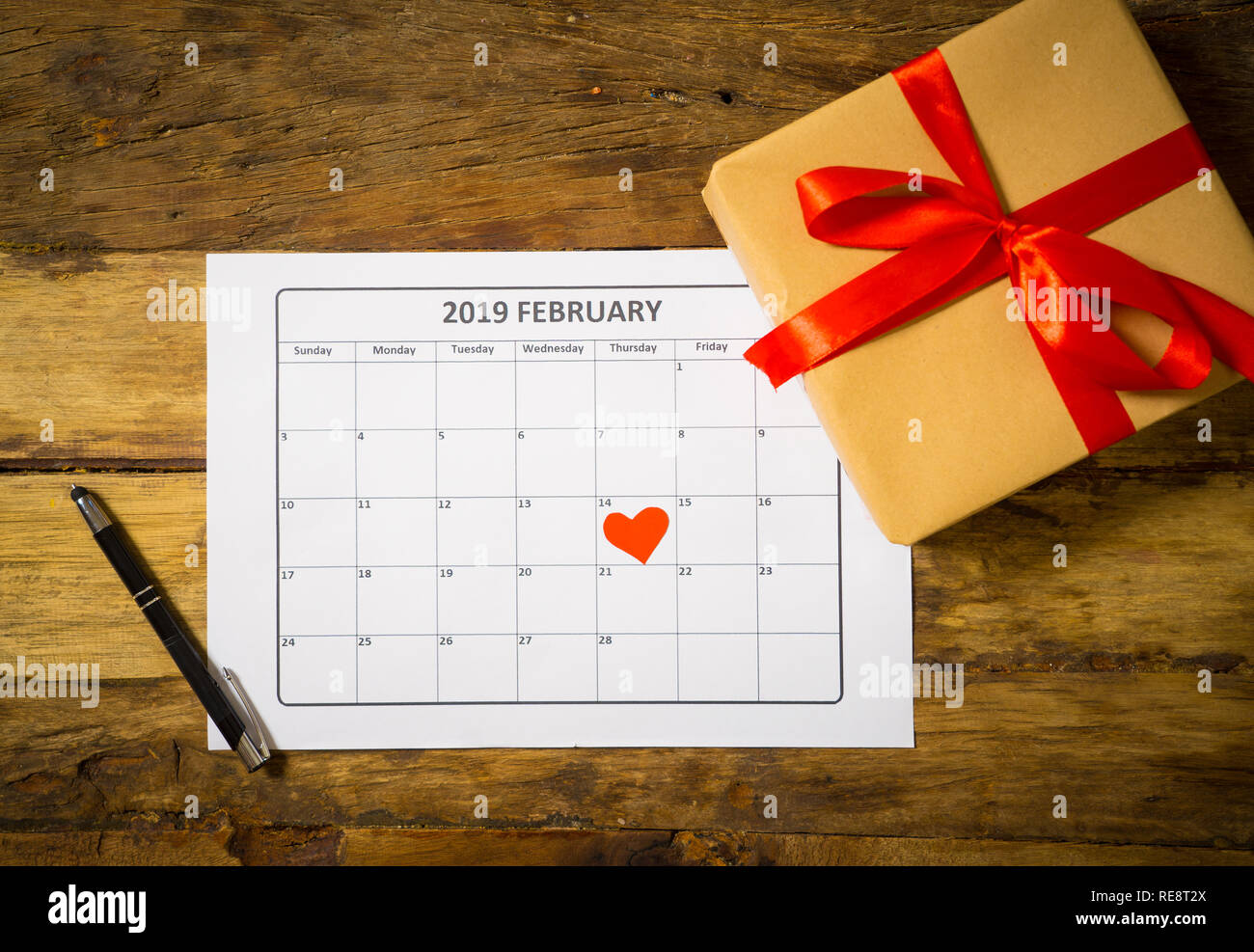 Image conceptuelle d'un calendrier février 2019 coeur sur le 14 ème et le présent gift wrapped with red ribbon sur table vintage rustique prêt pour saint Valen Banque D'Images