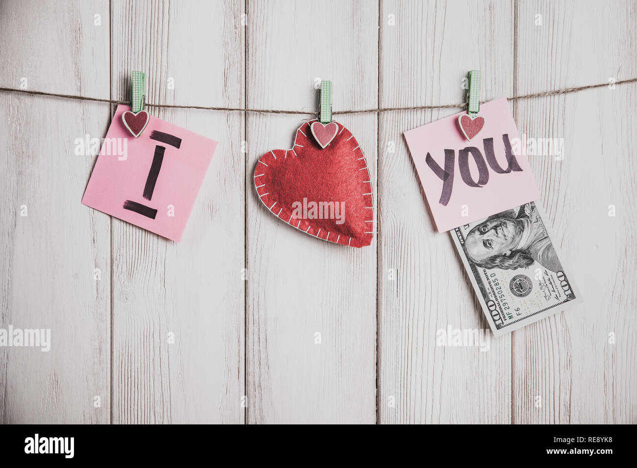 Carte de Saint Valentin. Coeur et feuilles de papier sur la corde avec des mots d'amour sur fond de bois blanc Banque D'Images