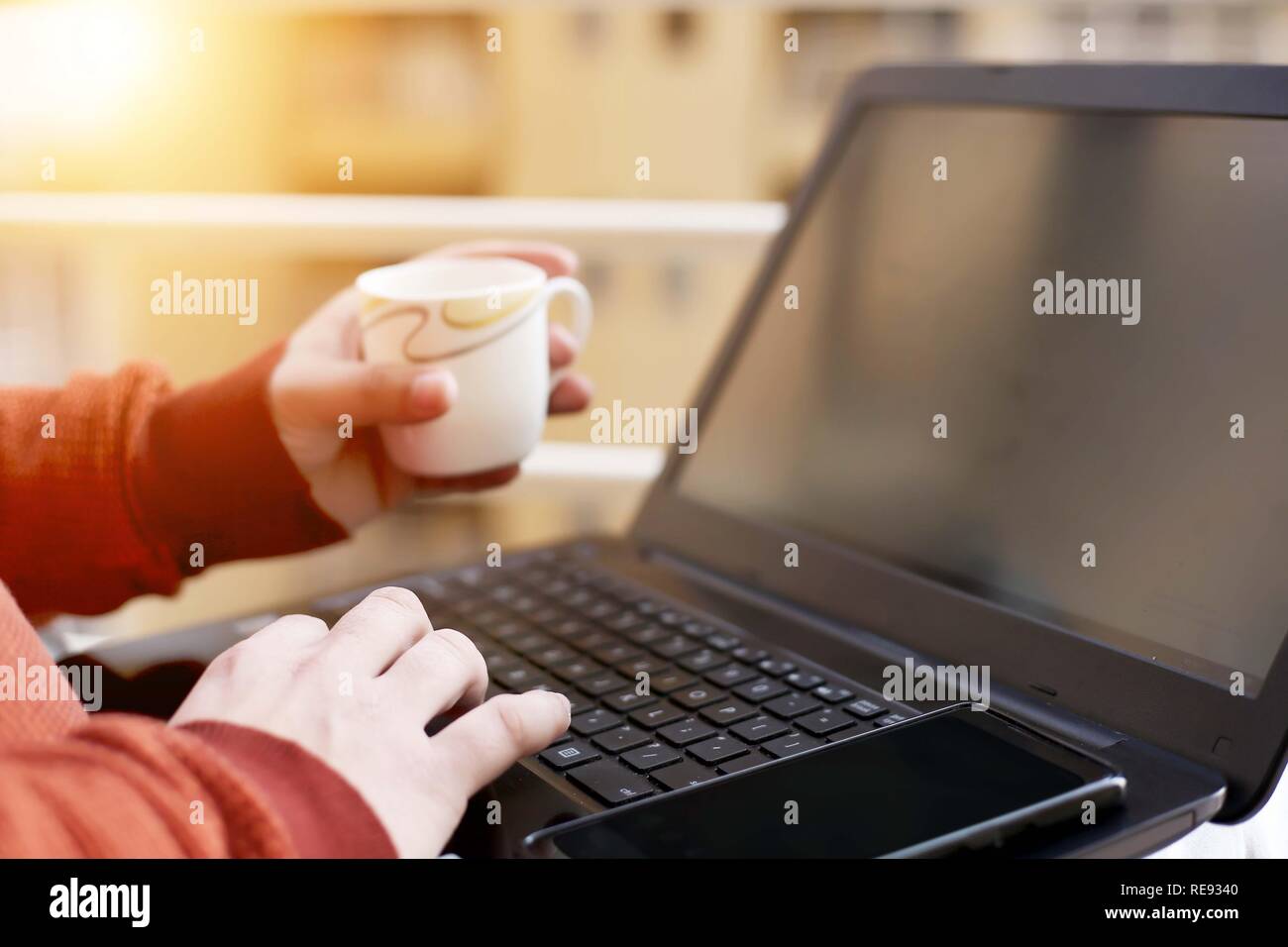 L'homme est de travailler sur l'ordinateur portable avec holding cup dans la main. Banque D'Images