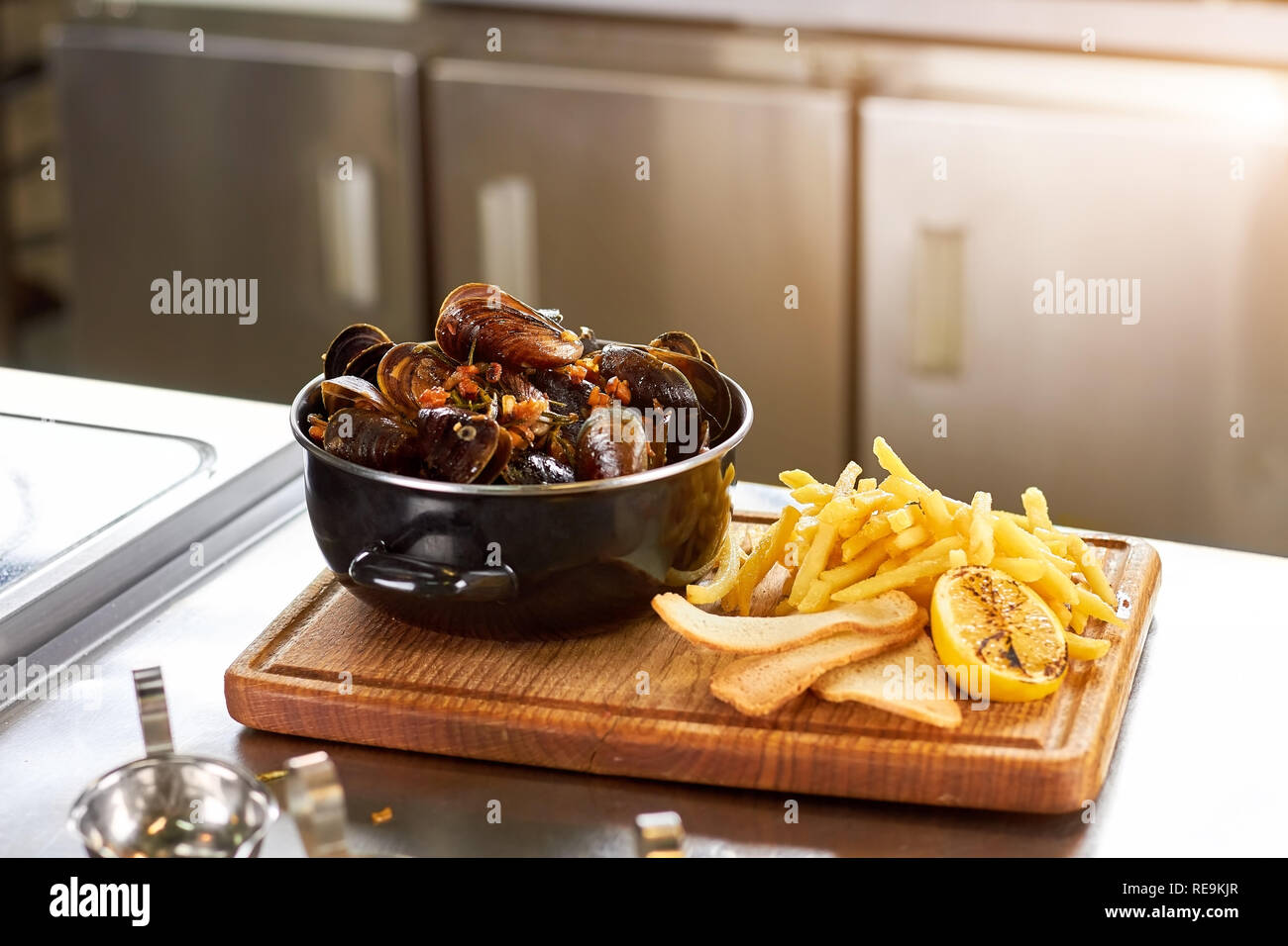 Plat avec des moules et des frites. Plat de charcuterie - sausepan de moules, frites, pain et citron. Banque D'Images