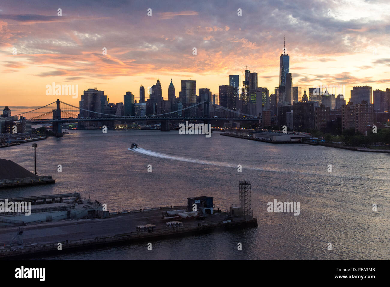 Un bateau traverse l'East River, en face de la Manhattan skyline at sunset Banque D'Images