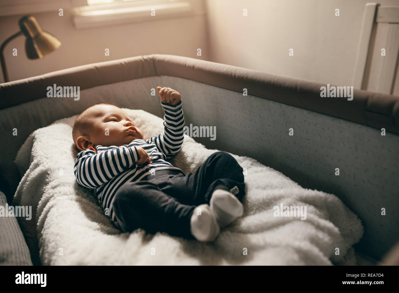 Bebe Couche Dans Un Berceau De Chevet Demenagement Ses Mains Bebe Couche Dans Un Lit De Bebe A La Maison Avec La Lumiere Du Soleil Qui Tombe Sur Lui Photo Stock