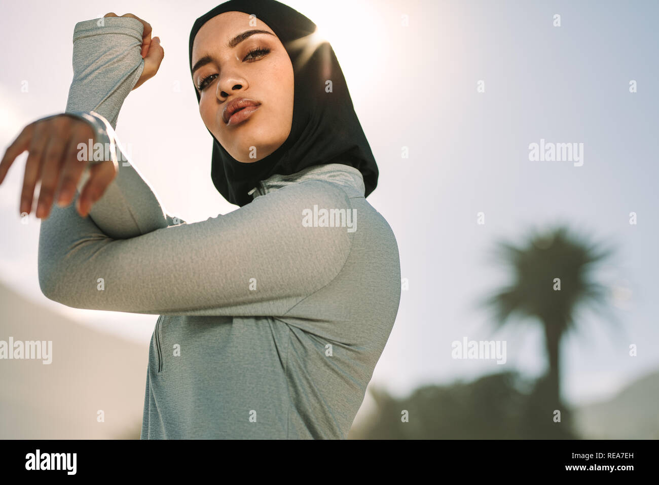 Les jeunes de la sportive en hijab étend ses bras et en regardant la caméra. À l'extérieur, dans l'exercice femmes musulmanes matin. Banque D'Images