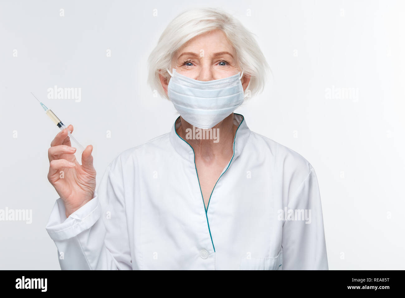 Femme médecin senior studio isolé sur mur blanc tenant la seringue d'injection d'anti-vieillissement Banque D'Images