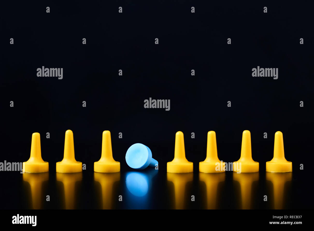 Le concept de l'individualité. Jeu de société bleu figure tombé hors de rangée de chiffres jaune Banque D'Images