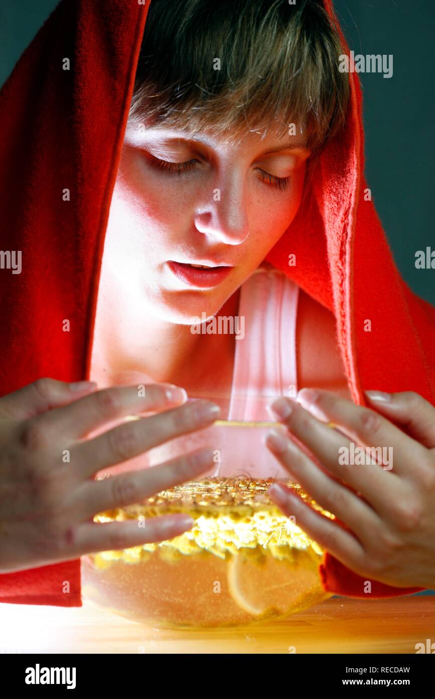 Jeune femme inhaler les vapeurs d'une infusion à base de camomille, fleurs séchées comme remède contre le rhume Banque D'Images