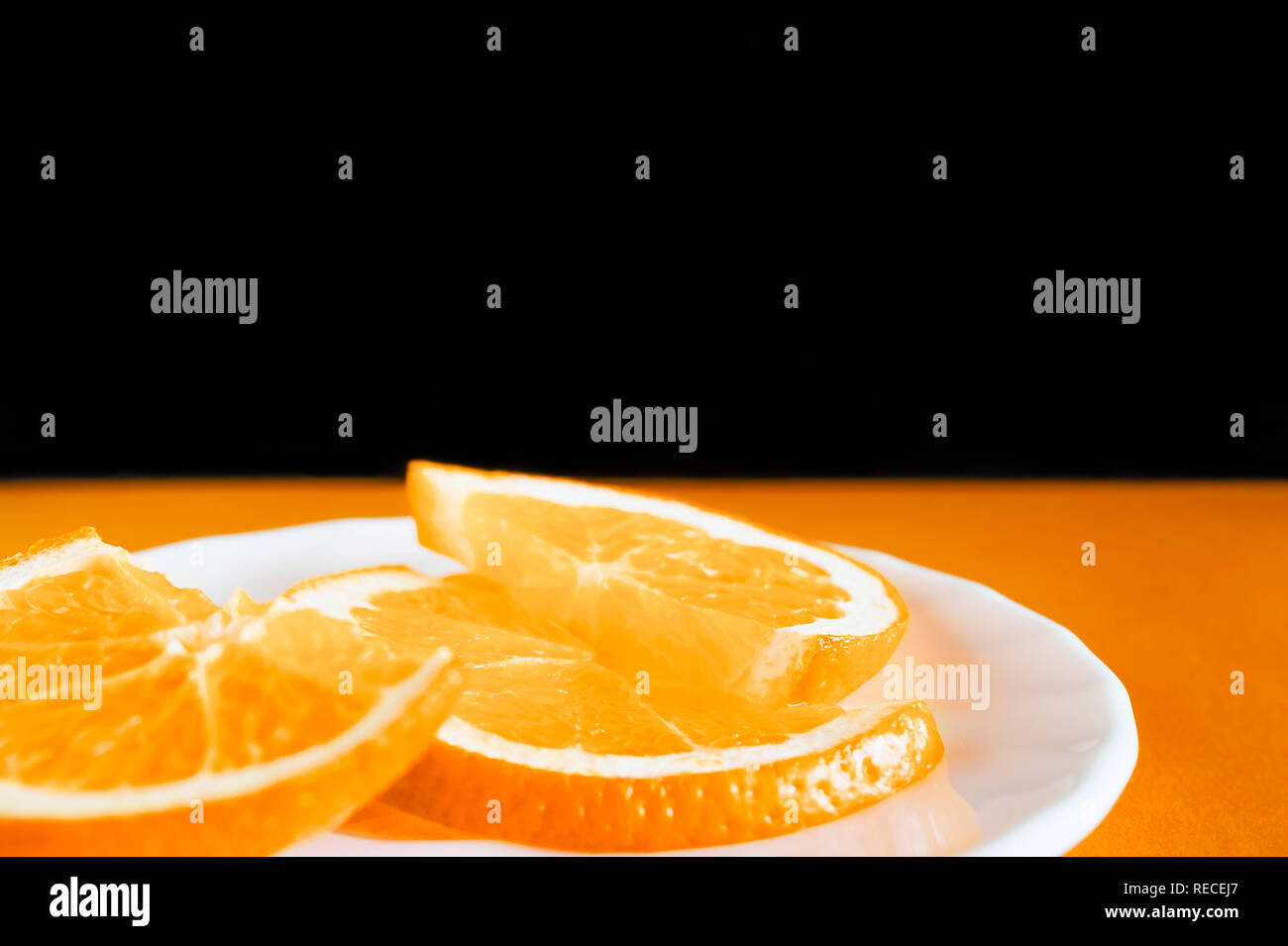 Tranches d'Orange dans une assiette blanche et noire sur fond orange. Aliments biologiques sains, petit-déjeuner, les ingrédients Concept avec Copy-Space Banque D'Images