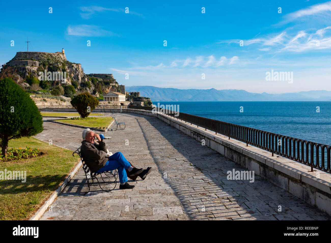 La ville de Corfou Corfou Grèce un couple de personnes âgées se trouve le long de la mer près de l'ancienne forteresse de prendre au soleil Banque D'Images