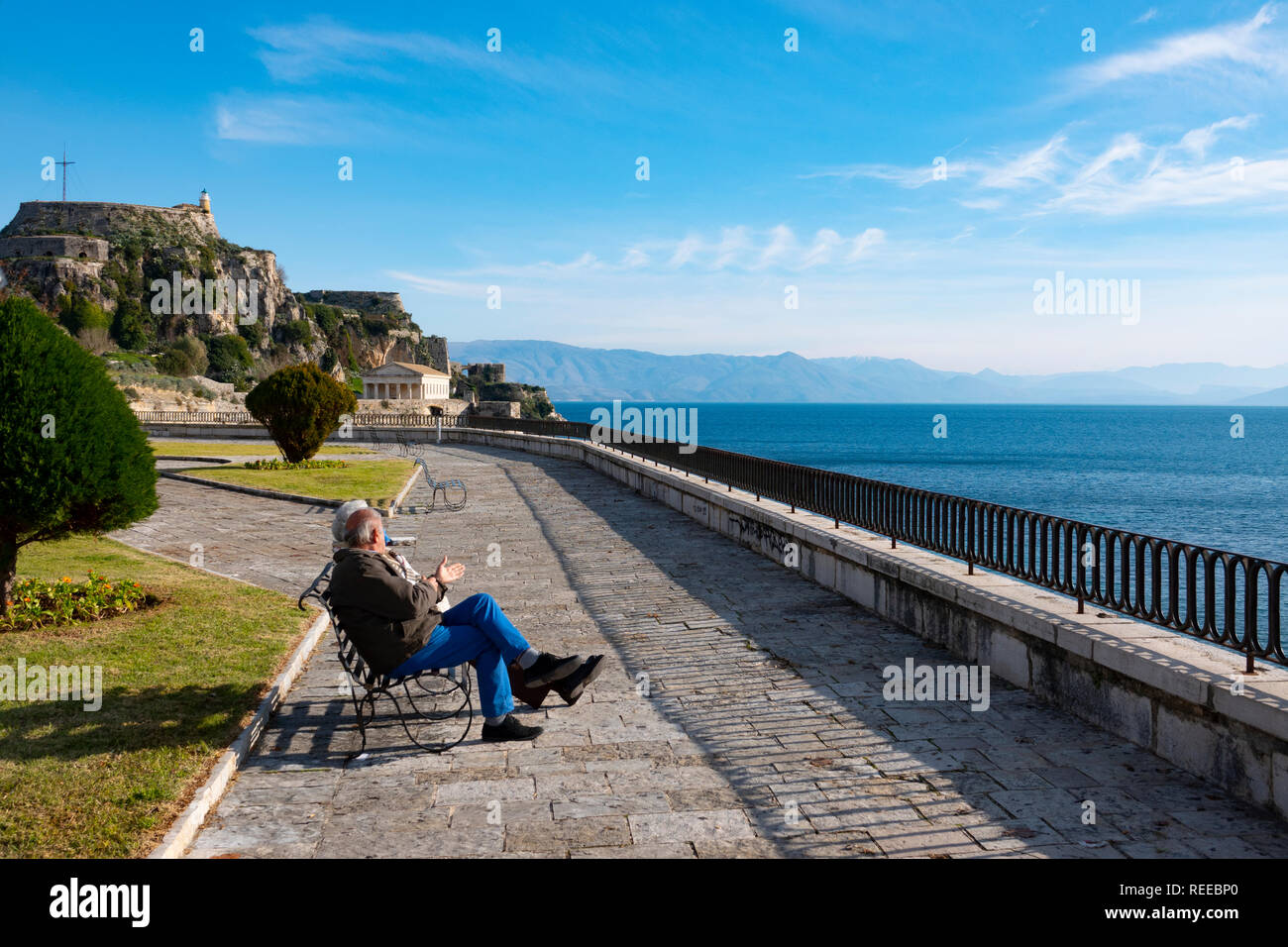 La ville de Corfou Corfou Grèce un couple de personnes âgées se trouve le long de la mer près de l'ancienne forteresse de prendre au soleil Banque D'Images