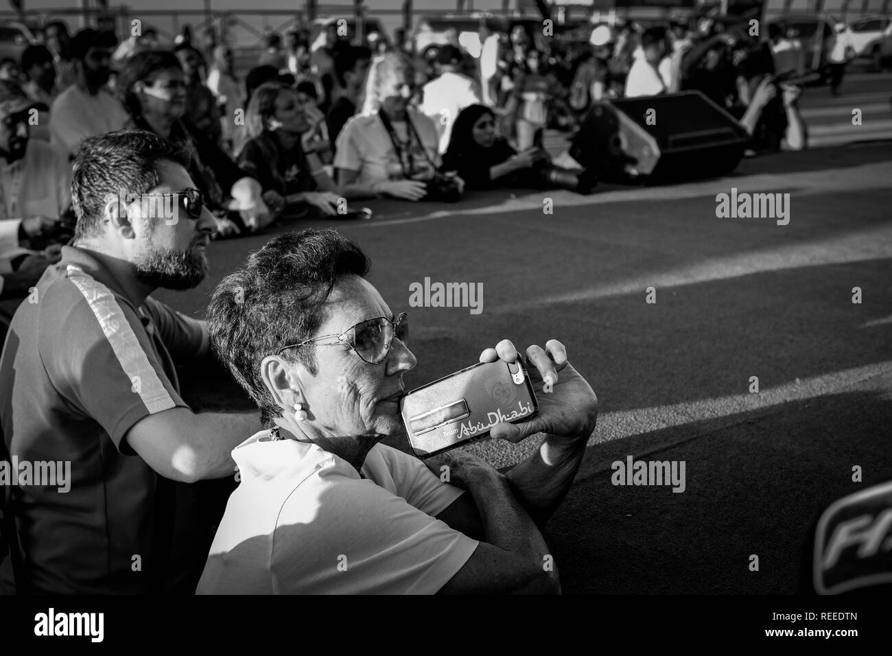 A senior woman holding smart phone avec Flipcase montrant le logo d'Abu Dhabi en regardant les concerts à F1H2O Racing Banque D'Images