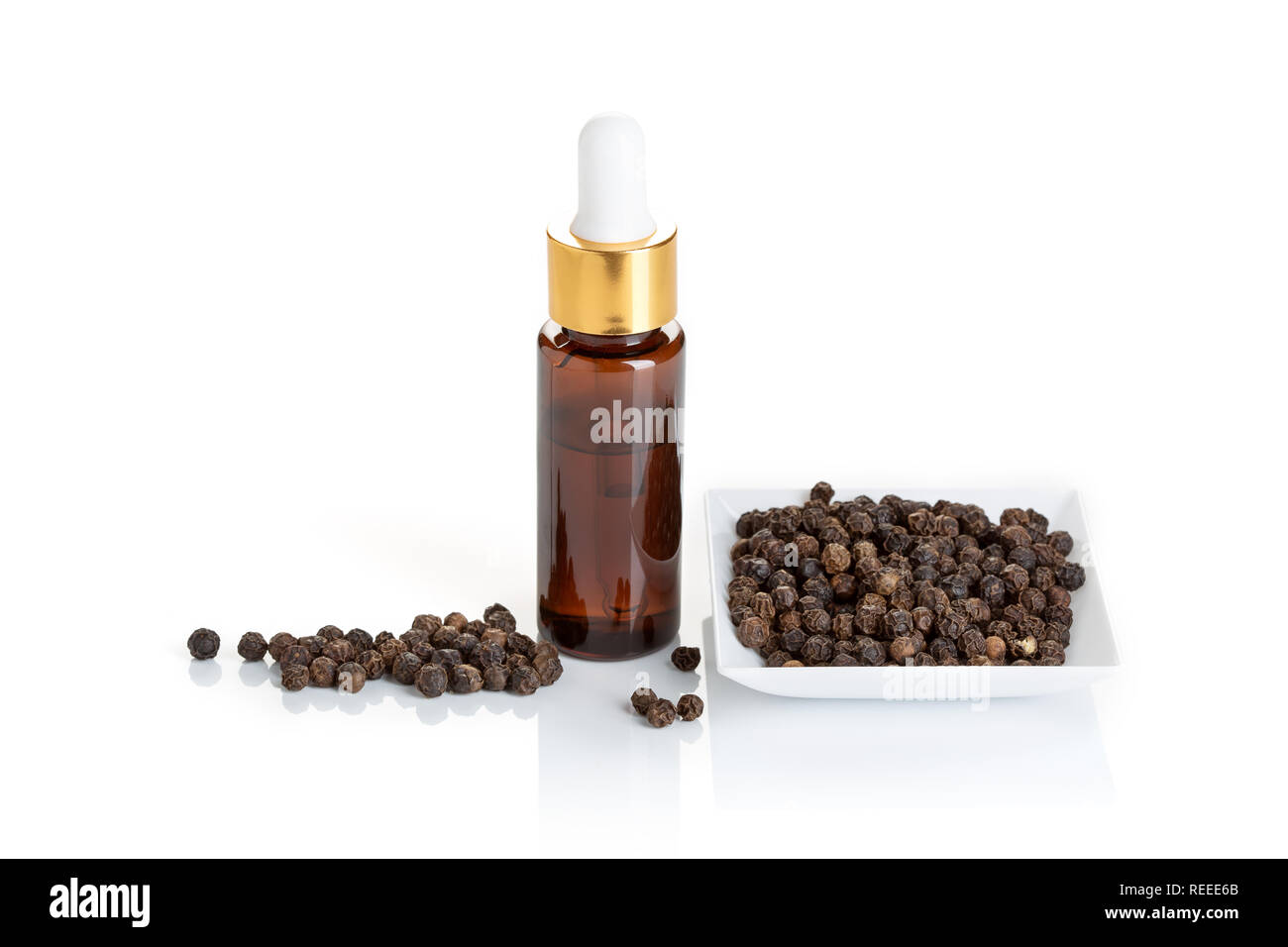 L'huile essentielle de poivre noir isolé sur fond blanc. Bouteille d'huile poivre noir avec compte-gouttes pour la beauté, soins de la peau, bien-être et à des fins médicinales. Banque D'Images
