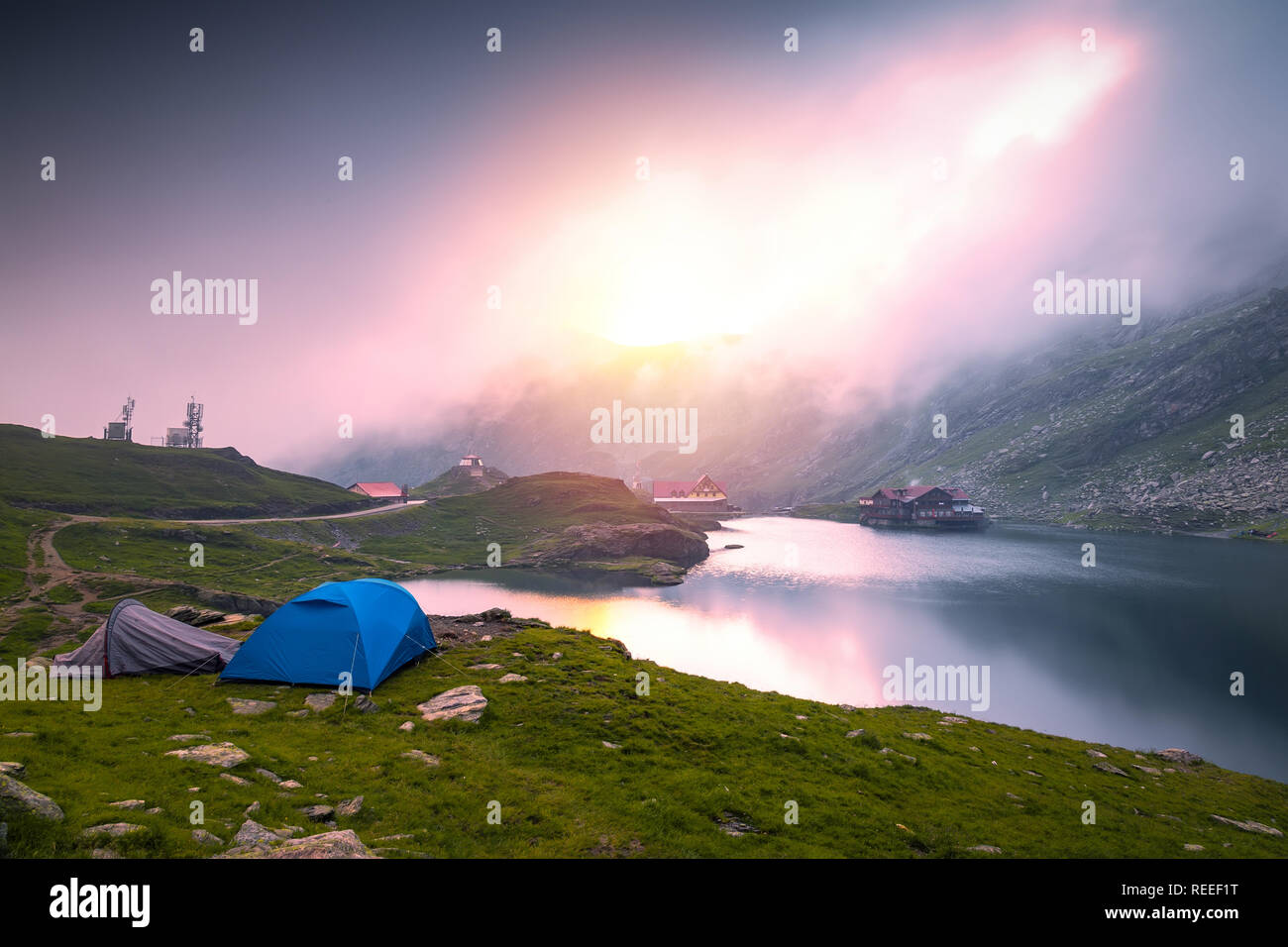 Lever du soleil sur le lac Balea glaciaire dans un matin brumeux. Tentes situé près de Balea Lac sur jour brumeux à Transfagarasan, Roumanie. Banque D'Images