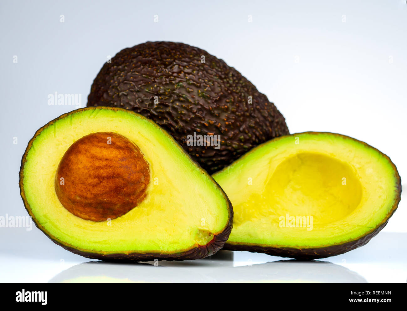 Avocat avec seed isolé sur fond blanc. Source d'oméga 3 à partir de la nourriture naturelle. Des aliments sains pour bébé. La moitié des morceaux de l'avocat organisée avec beau Banque D'Images