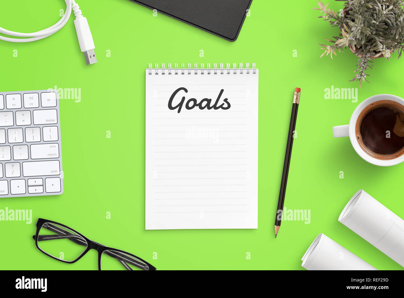 La préparation de la liste des objectifs d'affaires. Bureau bureau avec clavier, lunettes, tasse de café, des projets. Vue d'en haut. Banque D'Images