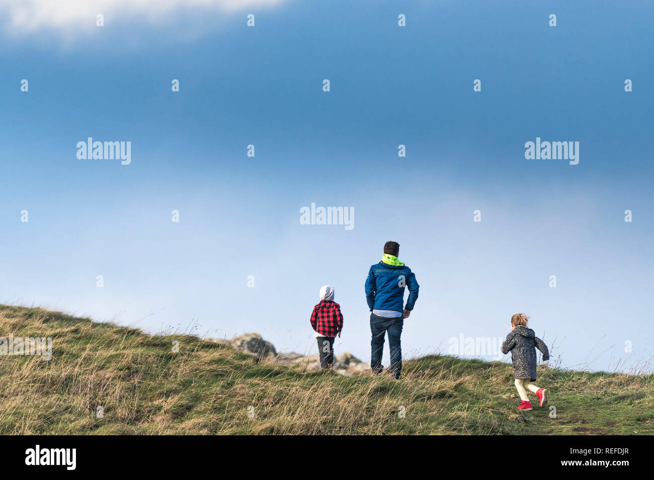 Un père et ses deux enfants à monter une colline dans la campagne. Banque D'Images