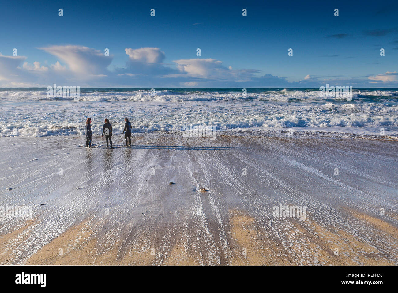 Les gens en combinaisons debout sur le rivage à la plage de Fistral Newquay en Cornouailles. Banque D'Images Les gens en combinaisons debout sur le rivage à la plage de Fistral Newquay en Cornouailles. Banque D'Images