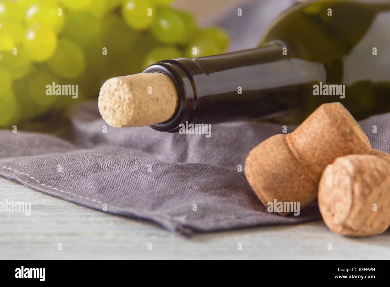 Bouteille de vin de raisins verts, sur une table en bois blanc. Banque D'Images