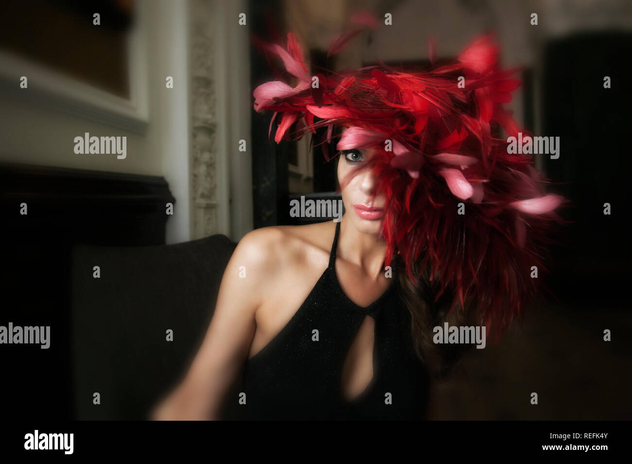 Photographie de mode de modèle de maturité wearing red feather fascinator Banque D'Images