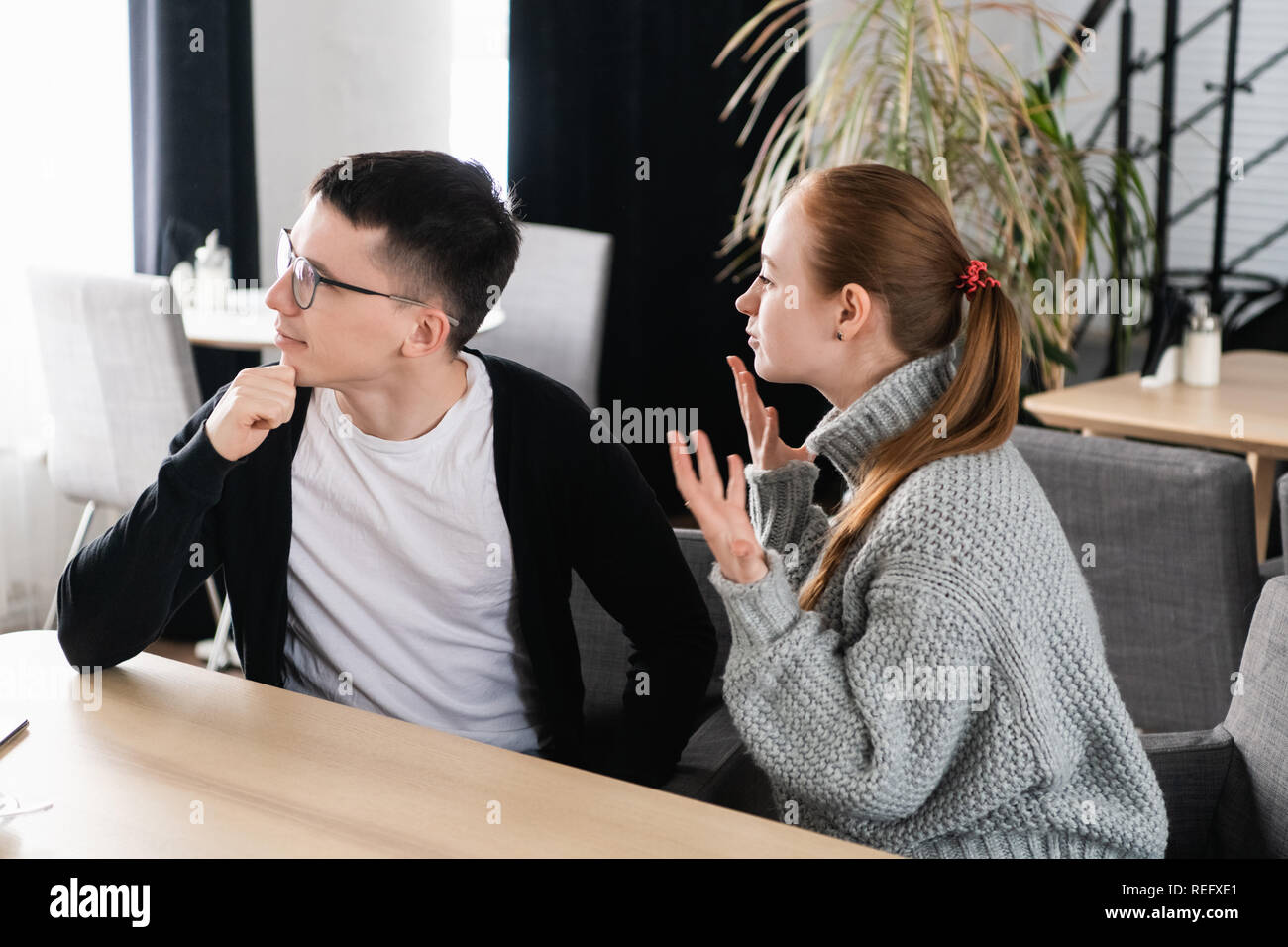 Angry couple arguing assis sur un canapé au café. L'homme ne tient pas compte de sa petite amie Banque D'Images