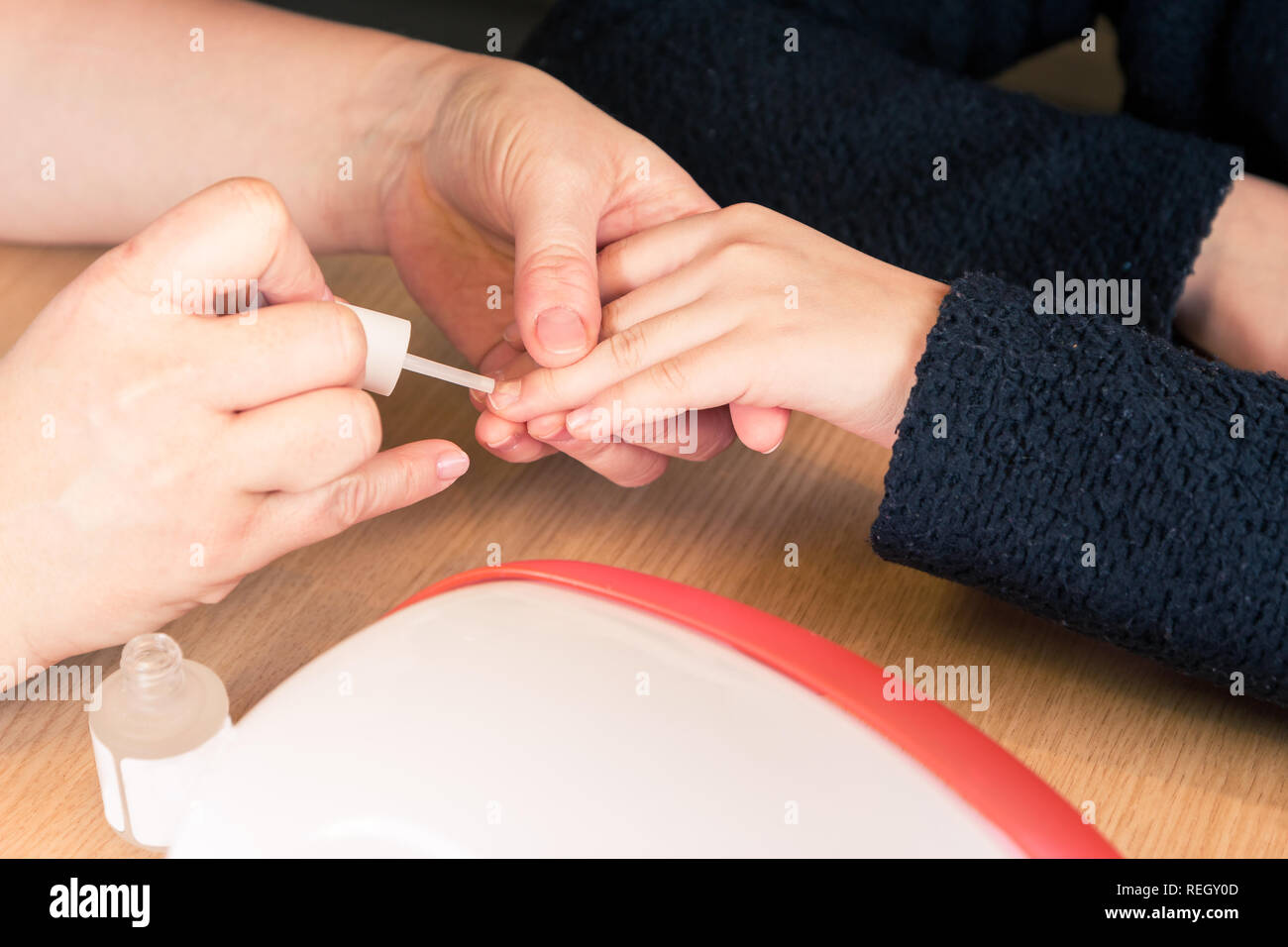 Close up of hands holding a jeunes filles main tandis que l'application de vernis à ongles transparent, processus et les ongles manucure Banque D'Images