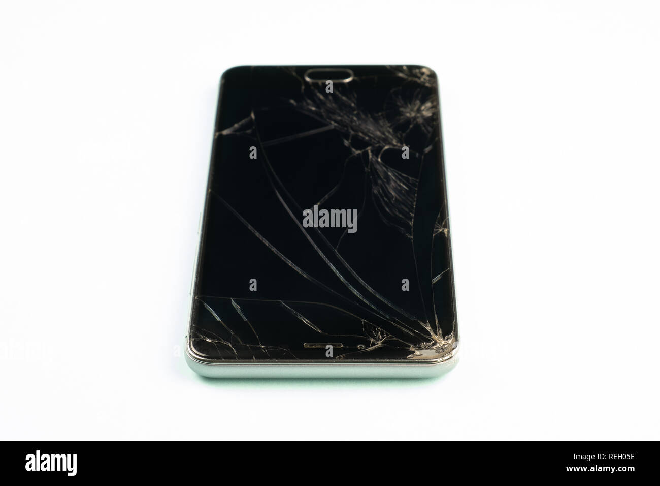 Téléphone mobile avec écran noir cassé, vue du dessus. Smartphone endommagé en détresse dans l'arrière-plan vert pâle, faible profondeur de champ Banque D'Images