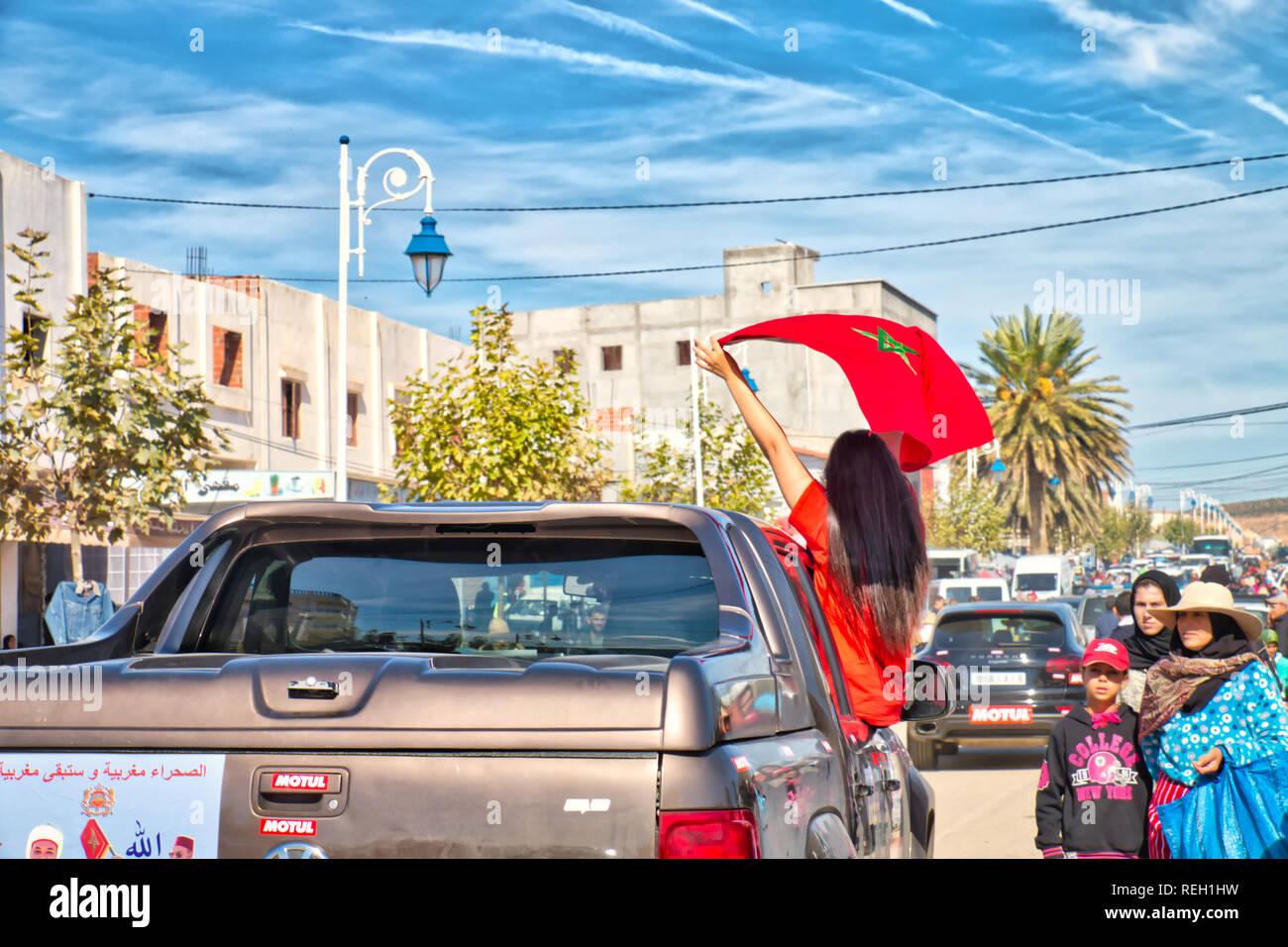 Oued Laou, Chefchaouen, Maroc - le 3 novembre 2018 : Une jeune femme brune aux cheveux longs, les vagues le drapeau marocain soulevées dans une voiture Banque D'Images