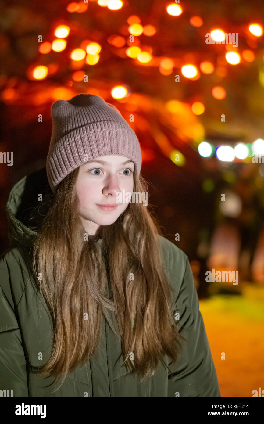 Belle fille à la recherche vers le bas sur la rue de la ville de nuit sur la toile de fond avec devanture rougeoyant. bokeh. L'espace de copie de l'inscription ou d'objets Banque D'Images