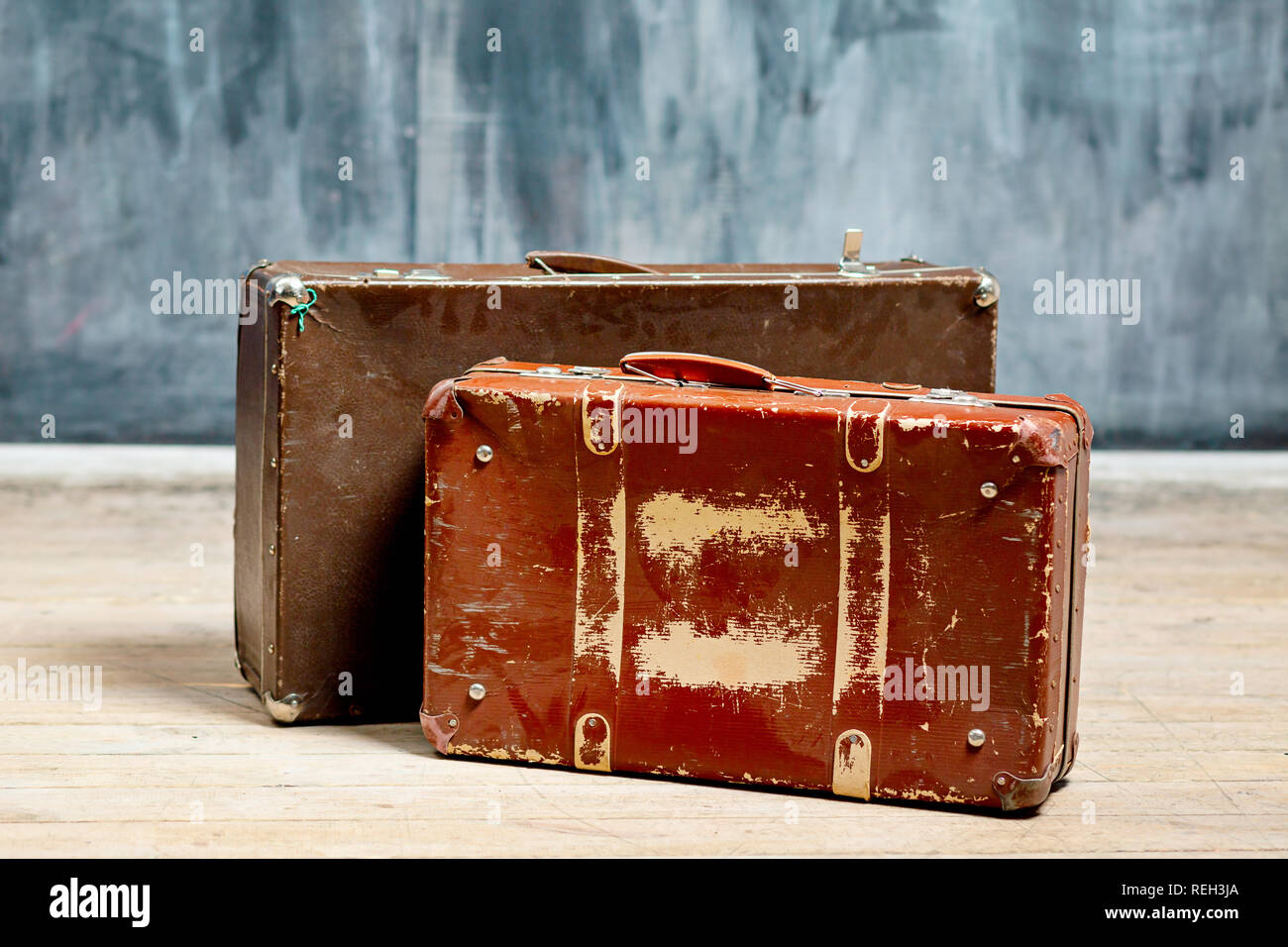 Deux valises marron foncé shabby près d'un mur à la craie Banque D'Images