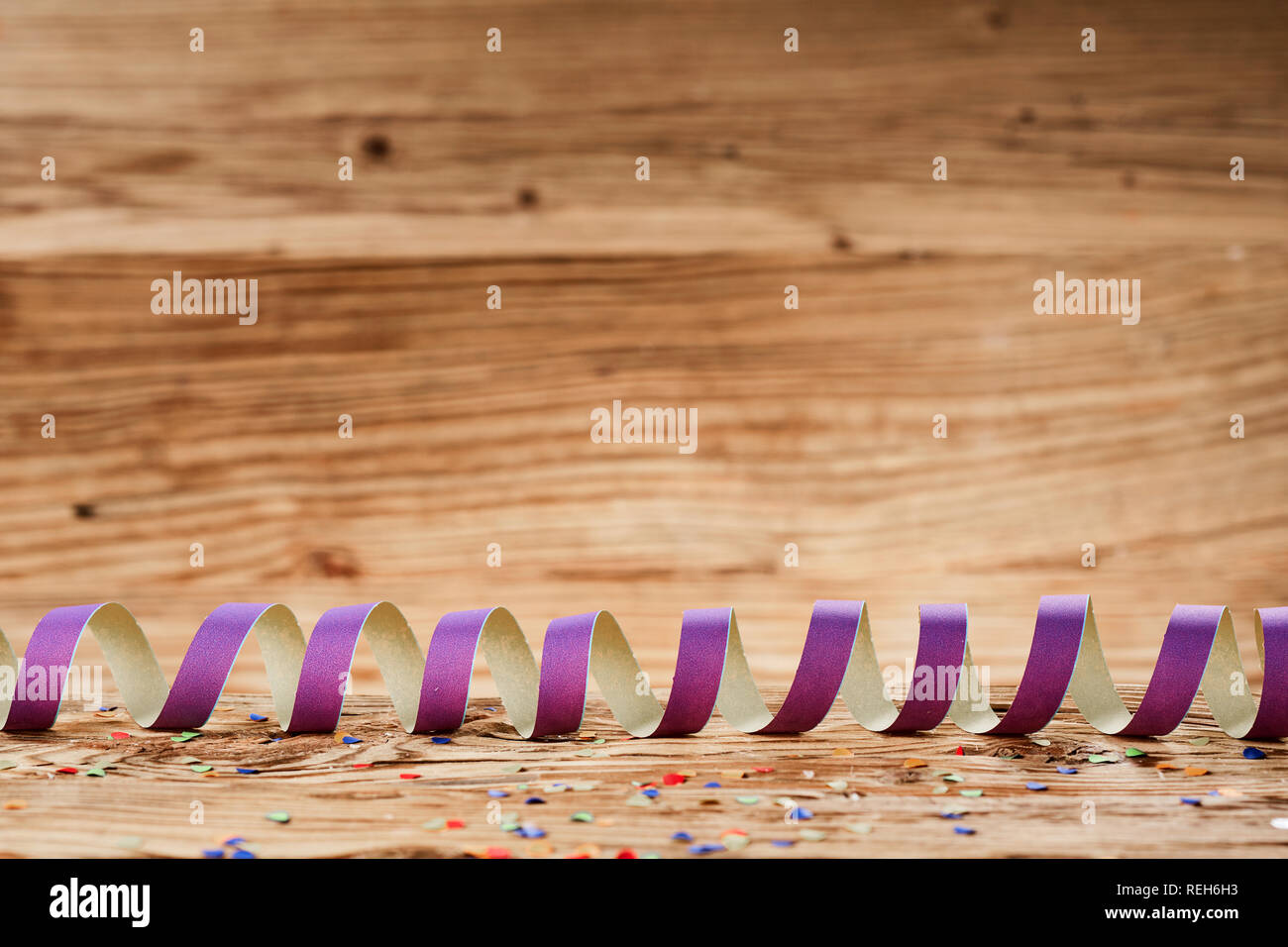 Concept de carnaval avec ruban coloré confettis éparpillés contre fond de bois Banque D'Images