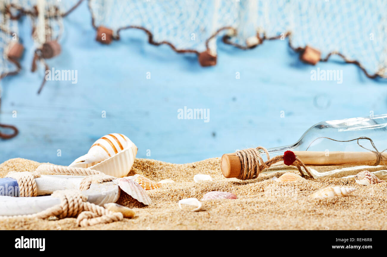 Plage Marine Nature morte avec mystère lettre dans une bouteille échouée sur le sable doré parsemé de coquillages et d'une vie sur l'anneau bleu avec copie espace Banque D'Images