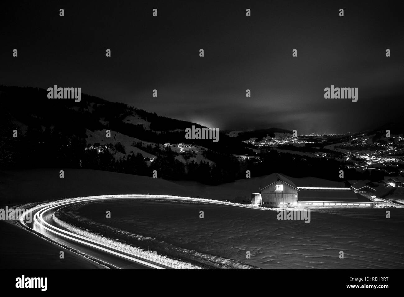La photographie de nuit long exposé les voitures qui circulent dans une route de montagne enneigée dans les Alpes d'Autriche. Banque D'Images