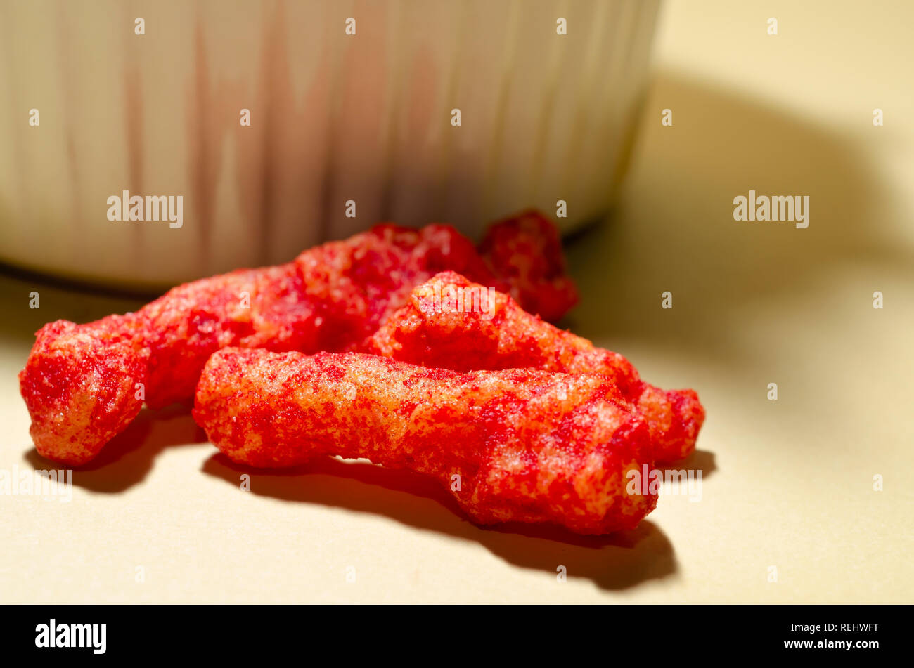 Une vue étroite de Flamin' Hot Cheetos révèle le chili épicé assaisonnement du fromage en poudre qui recouvre la semoule gonflée snack. Banque D'Images