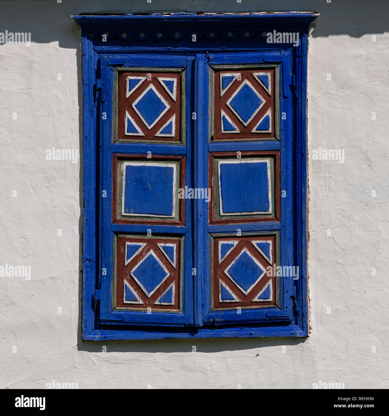 Détail d'un village traditionnel en Roumanie fenêtre peinte en bleu strident sur un mur de boue blanc arrière-plan. Banque D'Images