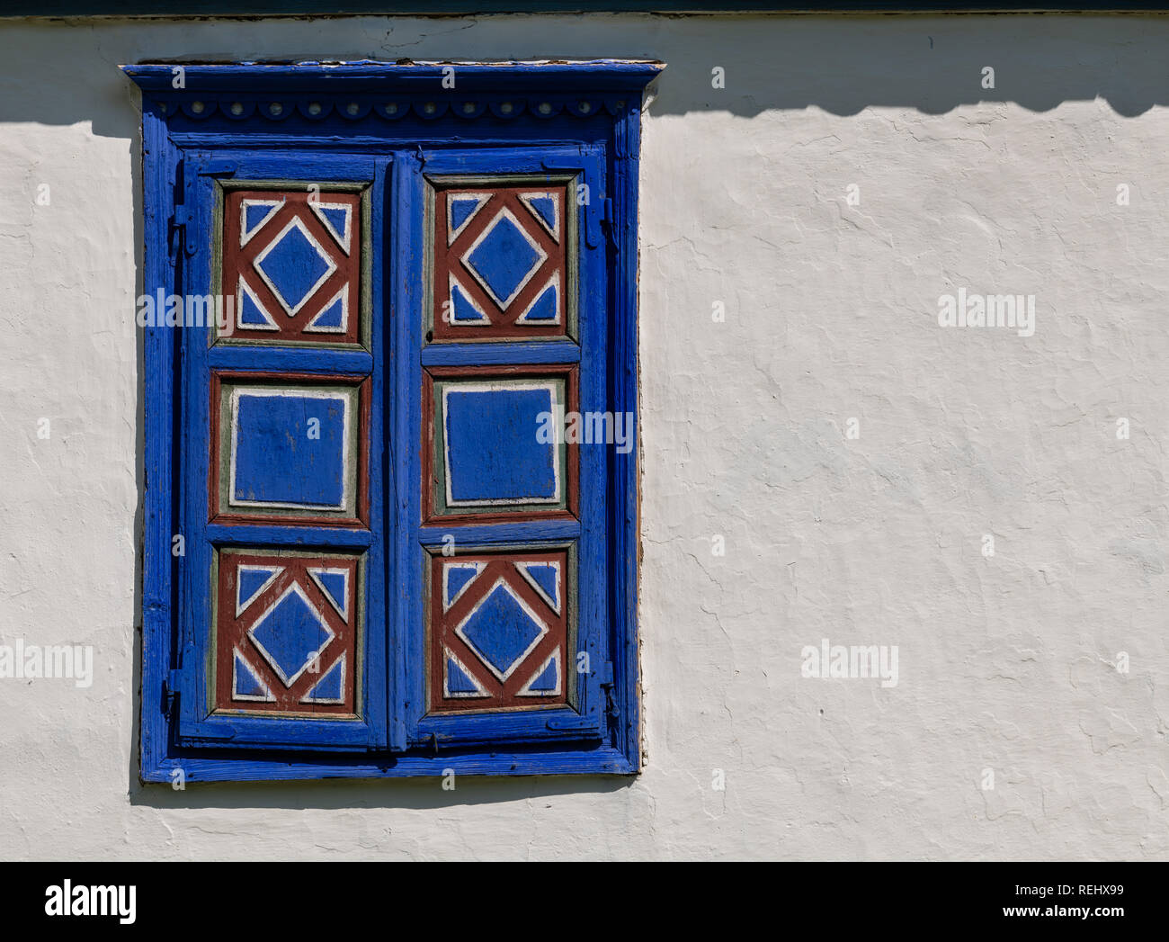 Détail d'un village traditionnel en Roumanie fenêtre peinte en bleu strident sur un mur de boue blanche avec copie espace. Banque D'Images