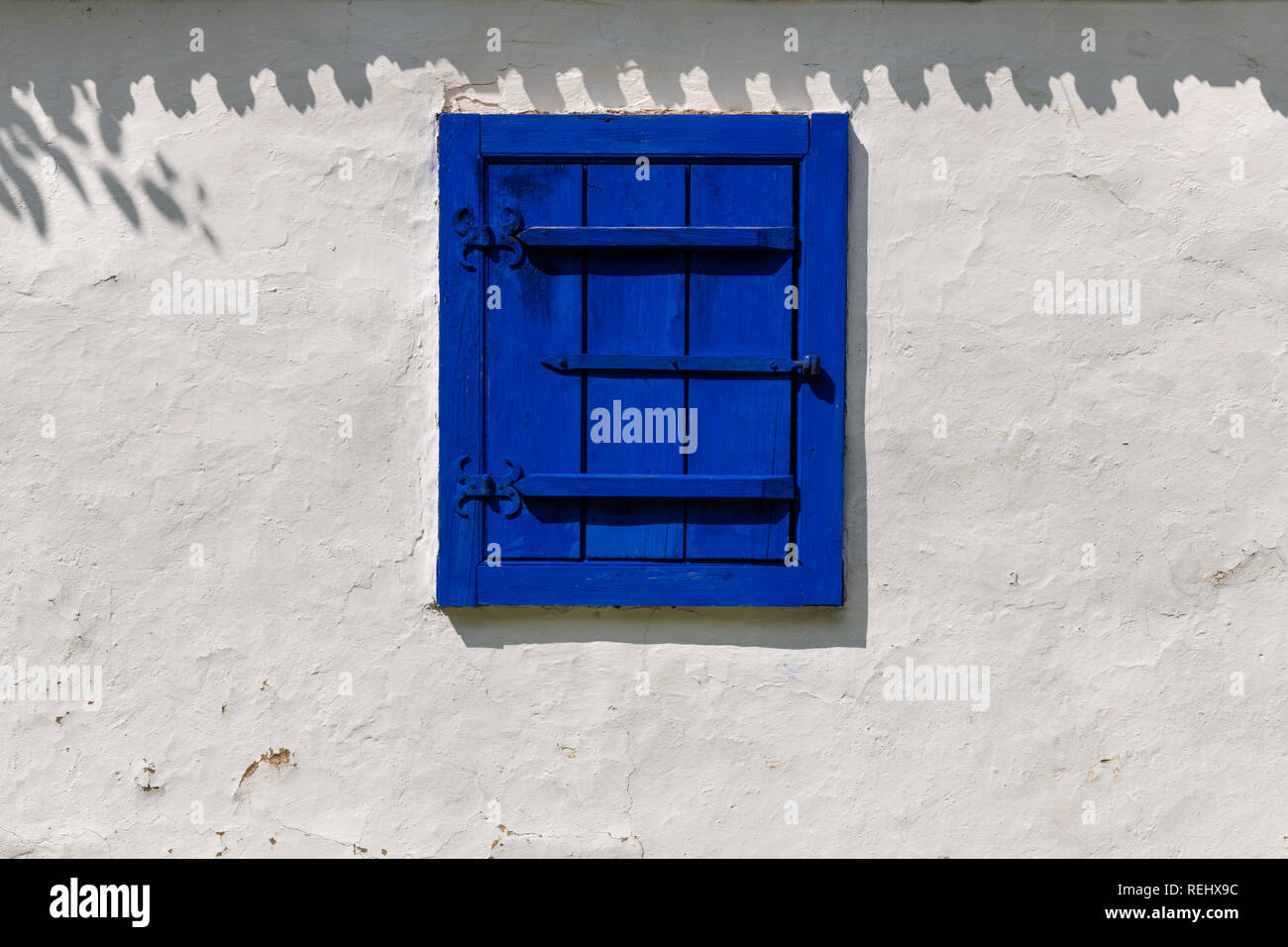 Détail d'un village traditionnel en Roumanie fenêtre peinte en bleu strident sur un mur de boue blanc arrière-plan. Banque D'Images