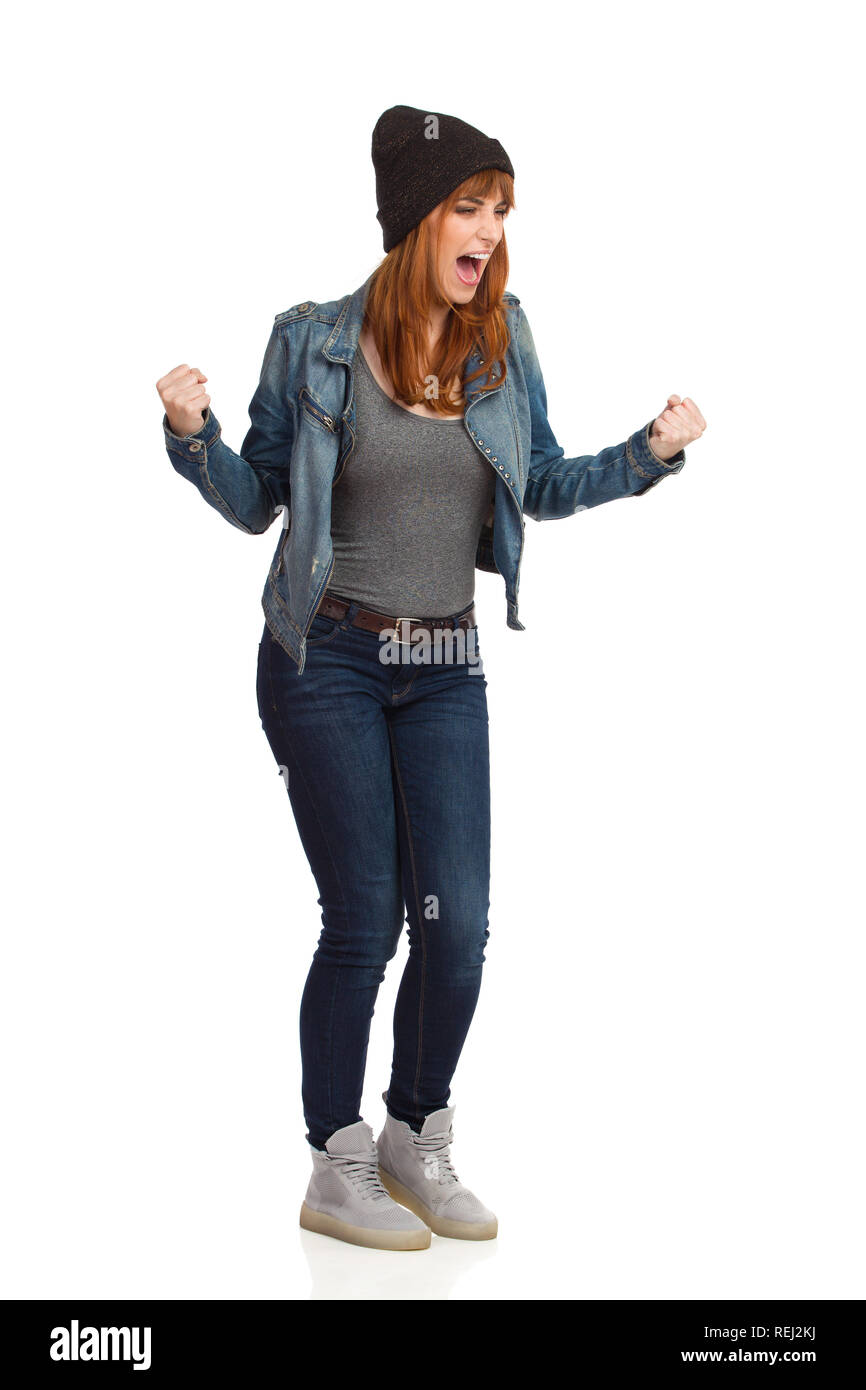 Jeune femme en colère en jeans et blouson cap est debout, work et crier. Studio pleine longueur shot isolé sur blanc. Banque D'Images