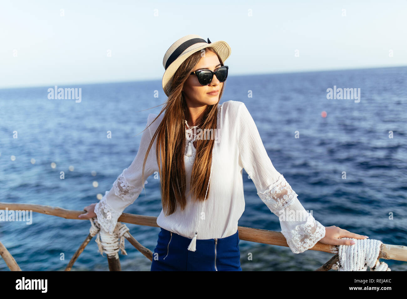 Jeune femme en lunettes de soleil et chapeau, robe d'été mignon en  permanent sans souci féminin à la pose d''un balcon avec vue magnifique sur  la mer, bénéficiant d'un paysage paysage Photo