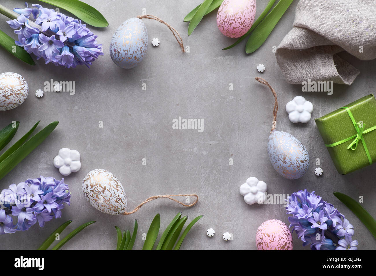 Mise à plat de Pâques avec les oeufs de Pâques, jacinthe bleu et fleurs en céramique blanche sur fond noir en lumière Banque D'Images