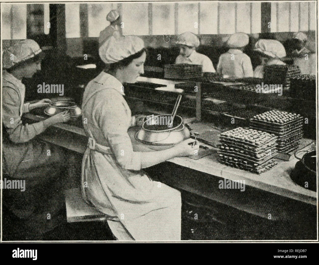 . Le cacao et le chocolat : leur histoire à partir de la plantation jusqu'au consommateur. Chocolat ; le cacao. Fabrication DU CHOCOLAT 151. Pour les filles, ou trempage, crèmes, etc. (MM. Cadbury Bros, Bournville.) a à peu près la même consistance que la crème. L'oper- ations jusqu'ici décrites sont effectuées par des hommes, mais la couverture des crèmes et l'emballage des chocolats finis dans des boîtes sont réalisées par les filles. La couverture est le travail léger nécessitant une touche délicate, et si, comme d'habitude, c'est fait dans des chambres spacieuses, est une occupation agréable. La jeune fille assise avec un petit bol de chocolat chaud devant elle, Banque D'Images