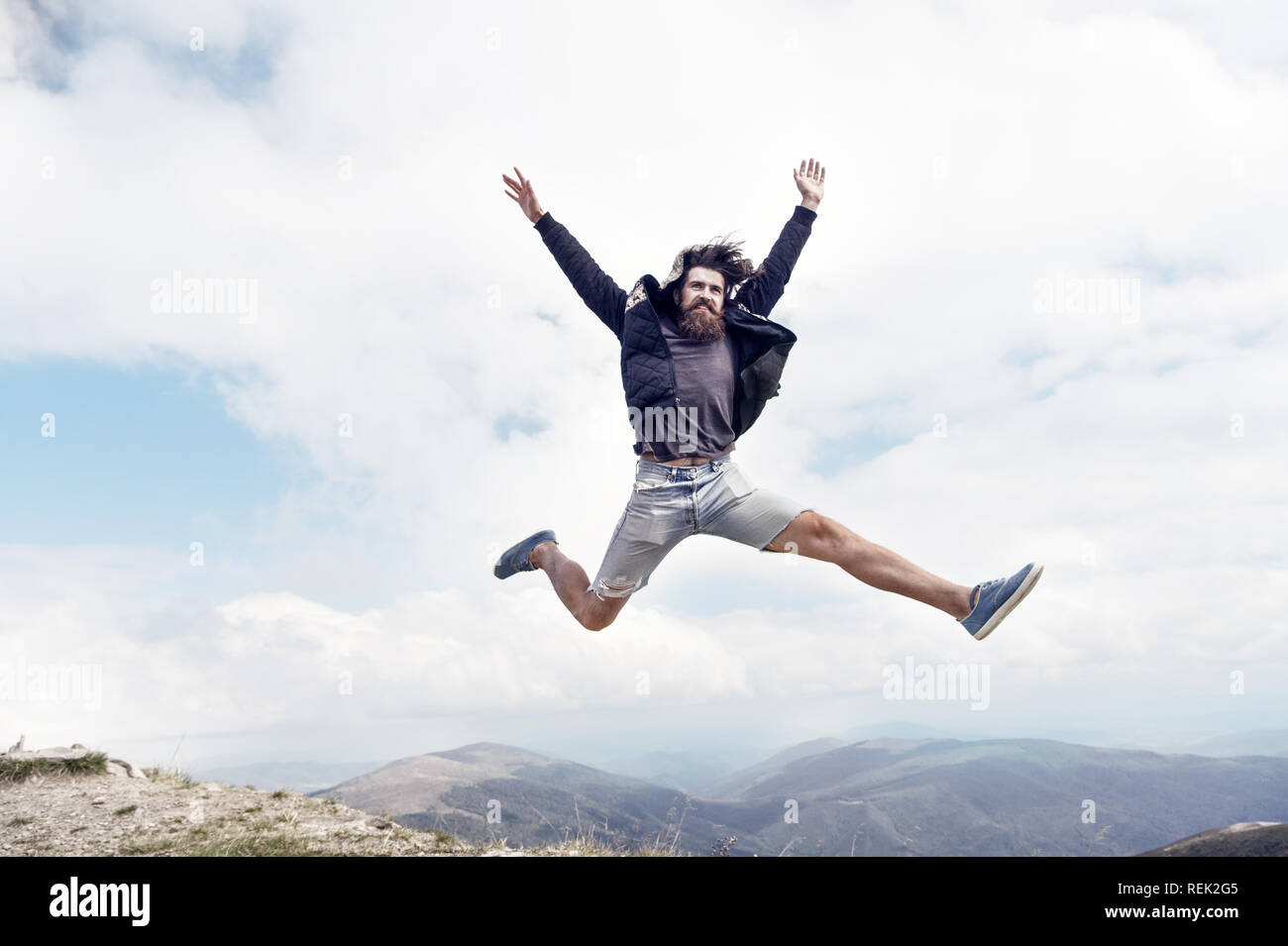 Homme barbu, longue barbe, brutal caucasian hipster avec moustache saut avec un visage heureux en montagne avec ciel nuageux, guy non rasé avec des cheveux ne coupe de barbe sur fond naturel Banque D'Images
