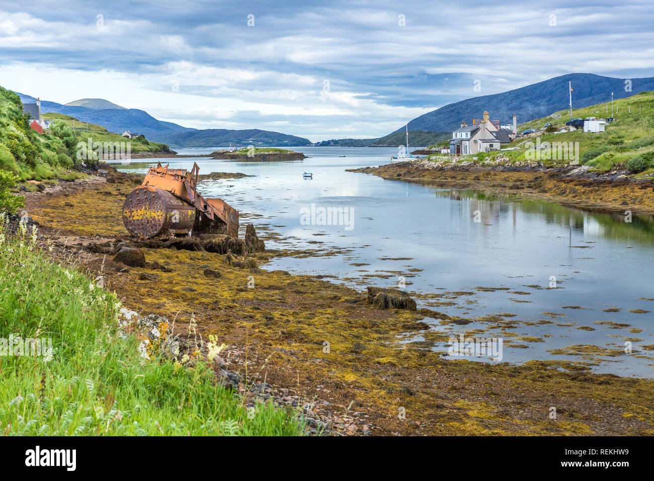 Vue sur la mer et le contraste des gîtes traditionnels et une vieille épave rouillée, à l'île de Scalpay, îles Hébrides, Ecosse, Royaume-Uni Banque D'Images