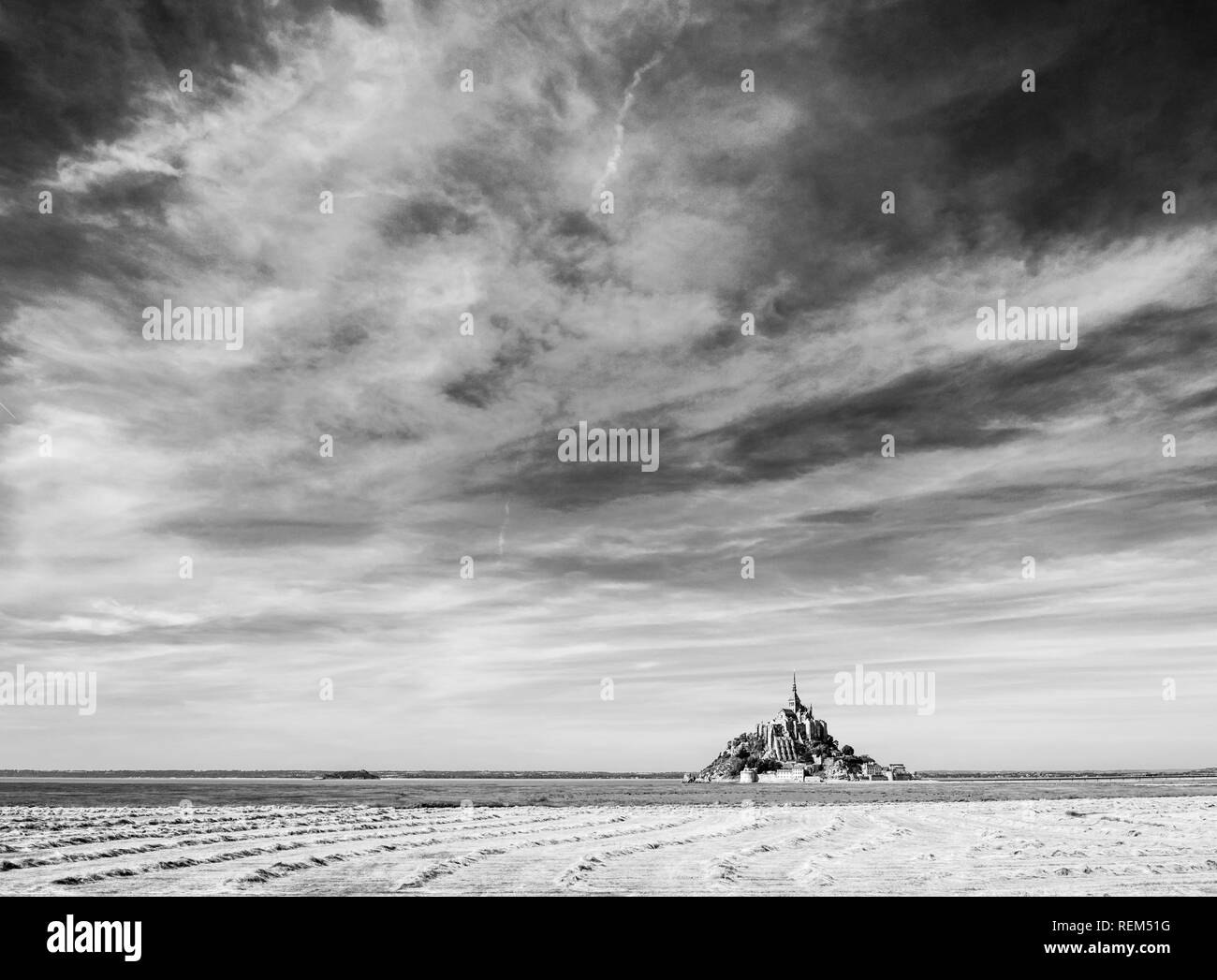 Le Mont Saint-Michel, l'île de marée en Normandie, France, avec séchage des andains de foin dans un champ en premier plan sous un ciel dramatique. Banque D'Images