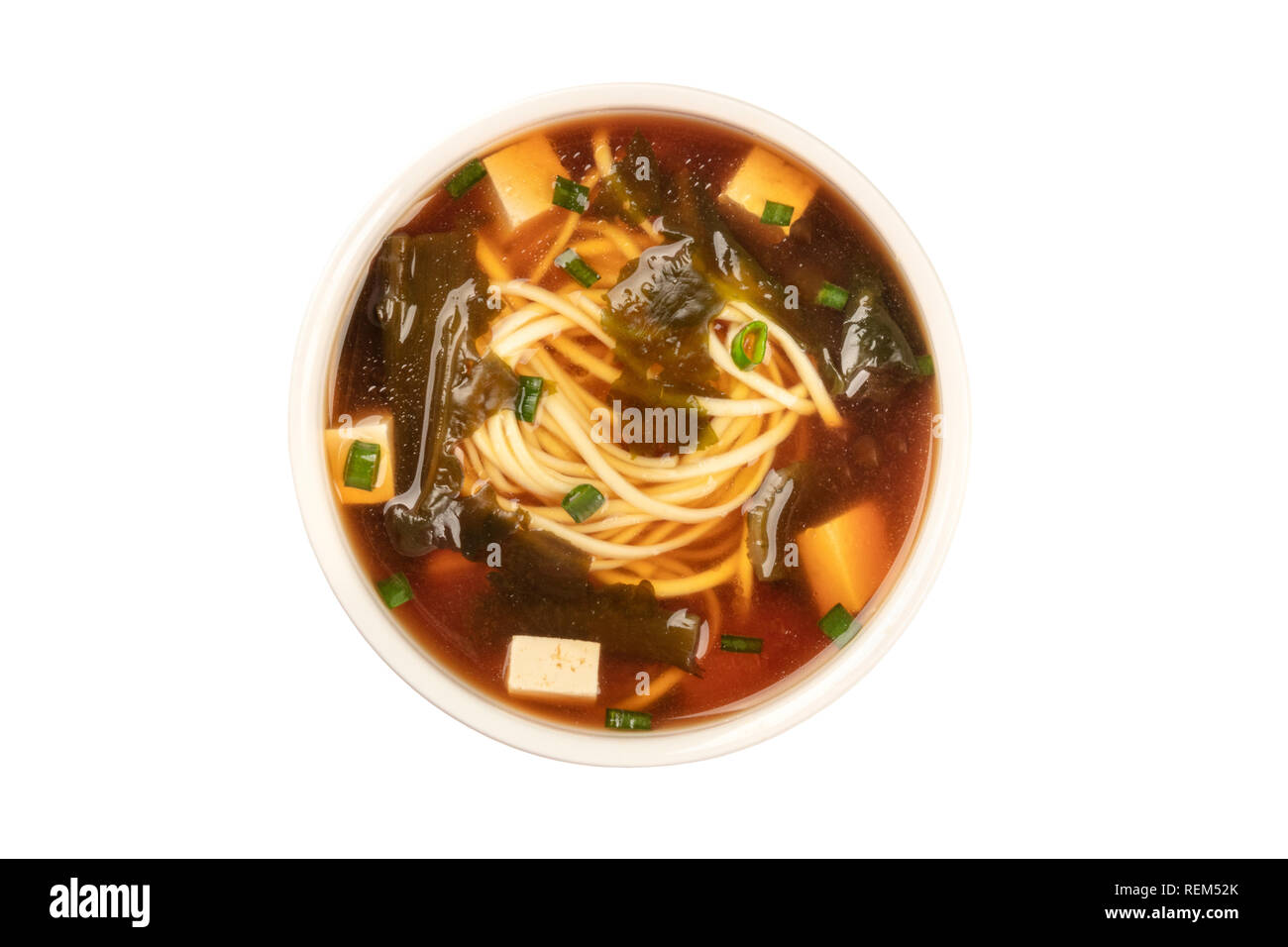 Un bol de soupe miso avec le tofu, les oignons verts, les nouilles, et d'algues wakame, tiré par le haut, isolé sur un fond blanc avec un chemin de détourage Banque D'Images