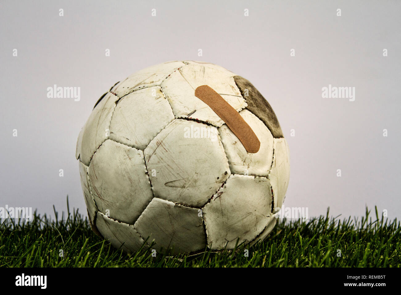 Ancien ballon de soccer avec l'aide de bande sur l'herbe avec fond blanc Banque D'Images