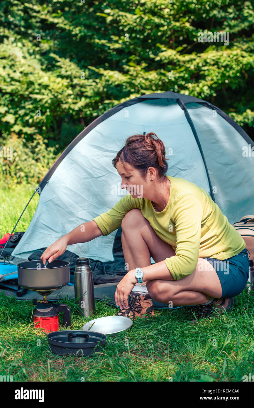 Passer un séjour sur le camping. Femme préparant un repas à côté de plein air tente Banque D'Images