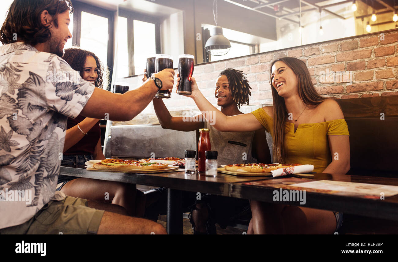 Groupe multiethnique de people toasting boissons non alcoolisées dans un café. Les hommes et les femmes assis à l'intérieur d'un restaurant toasting drinks. Banque D'Images