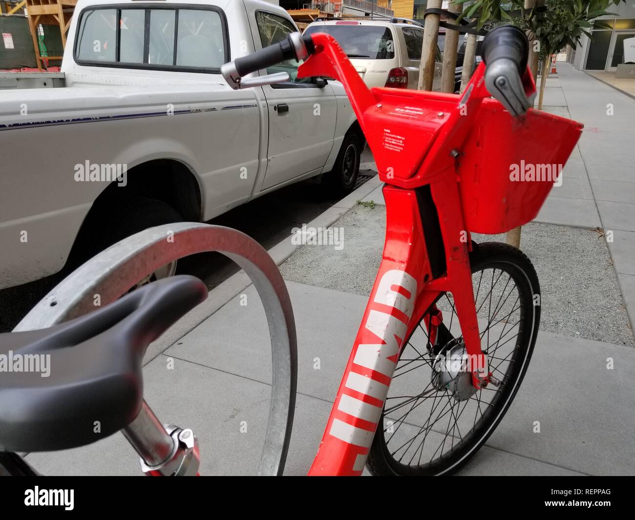 Photographie du gros plan d'une orange location propriété de la société de covoiturage, garée à côté d'un camion blanc, sur la 3e rue, en face de l'UCSF, Services de santé au travail situé dans le quartier de Mission Bay de San Francisco, Californie, le 29 octobre 2018. () Banque D'Images