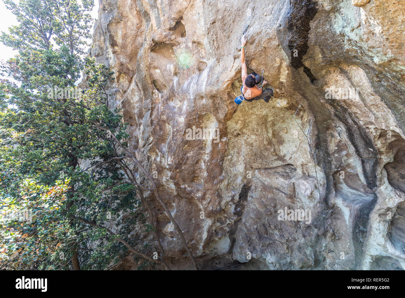 Pratiquer l'escalade sport extrême dans les Andes, au niveau d'une falaise. Un grimpeur mâle fait les mouvements durs avec ténacité et confiance Banque D'Images