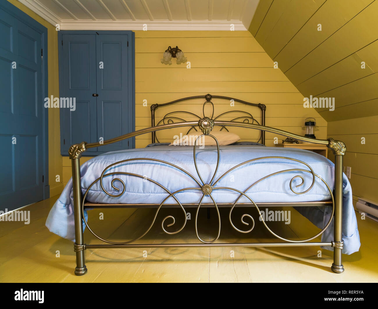 Lit double avec tête de lit métal laiton antique et au pied du lit dans la  chambre principale à l'étage à l'intérieur d'un ancien régime français 1809  maison de style cottage Photo