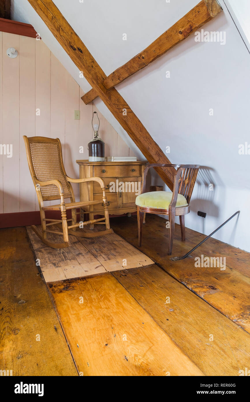 Meubles anciens en bois à haut dossier et une chaise berçante chaise  capitonnée jaune à côté d'une commode dans cette chambre mansardée à  l'intérieur de l'ancien régime Français home style 1809 Photo